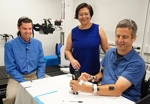 CNT research study participant Jon Schlueter (right) performs a grip-strength test while electrical stimulation is applied to his spine. CNT Co-Director Chet Moritz (left) and researcher Fatma Inanici