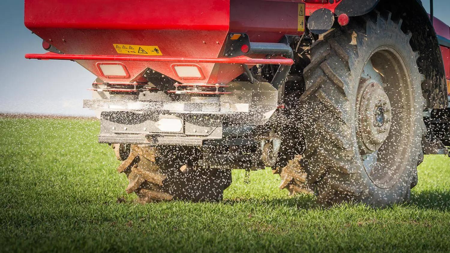 A tractor spreading fertilizer on the field